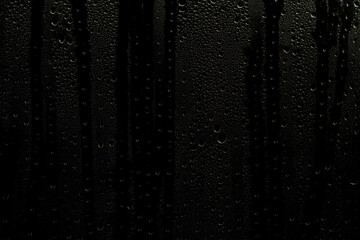 Wet window with water streaks. Glass with raindrops on a dark background. Background or overlay for use in design. - obrazy, fototapety, plakaty