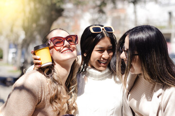 Three friends hug each other and smile on the street