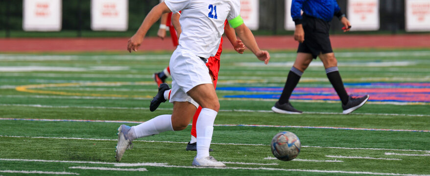 Soccer player in white uniform controlling the ball dribbling across the field during a game - Powered by Adobe