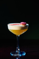 delicious frothy daiquiri with pink fresh flower on foam on black backdrop, concept