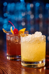 exotic caipirinha and negroni garnished with ice and fruits with bar on backdrop, concept
