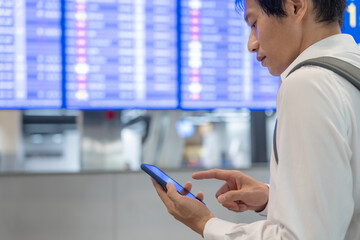 Business man using mobile phone to book plane ticket through online application, sitting on travel checking travel time on board at airport, travel, payment, due, booking, online, check in - obrazy, fototapety, plakaty