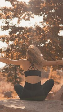 Fitness and yoga in the natural environment in the fall is a health dream that a woman makes come true. Vertical video. In autumn, in the midst of nature, a woman concentrates on performing a yogic