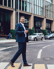 Cheerful boss with smartphone crossing road