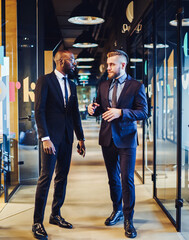 Serious adult multiracial colleagues having conversation in light office corridor