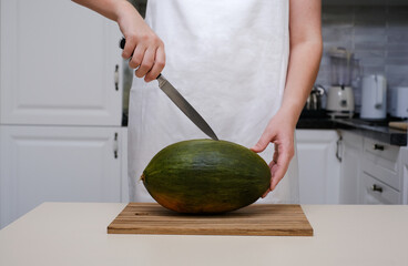 a cook in the kitchen cuts a ripe melon, close-up of hands