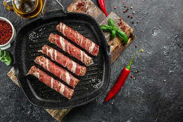 Pork wrapped in bacon in pan on a dark background. banner, menu, recipe place for text, top view