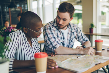 Couple preparing for trip with map in cafe