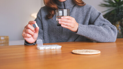 Closeup image of a woman holding pills and a glass of water