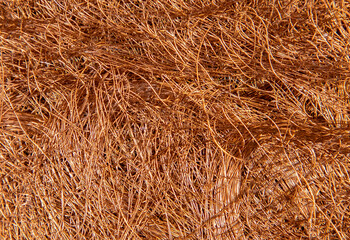 Many lacquered copper wires from the disassembly of a transformer coil in the foreground. Scrap copper for recycling