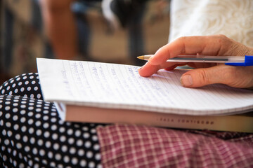 Close up of a person writing on a notebook. Adult person sitting on a sofa writing a text with an...