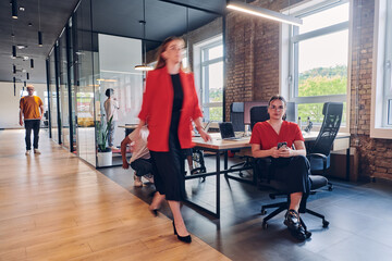 A diverse group of business professionals collaborates in a modern startup coworking center, utilizing a mix of paper-based and technological tools such as mobile phones and computers to collectively