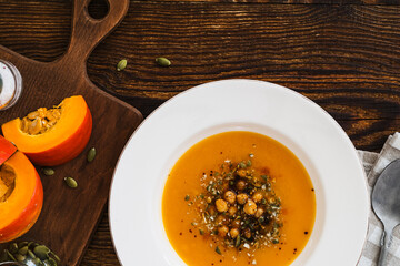 Bowl with vegan pumpkin and chickpea cream soup  on wooden table, directly above