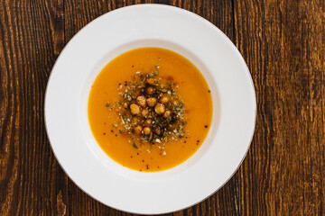 Bowl with vegan pumpkin and chickpea cream soup  on wooden table, directly above