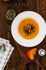 Bowl with vegan pumpkin and chickpea cream soup  on wooden table, directly above