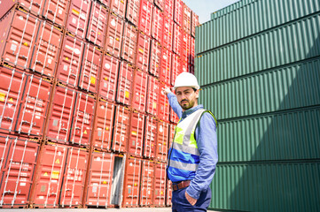 Portrait of Logistic engineer worker man standing in shipping container yard and crossed arms....