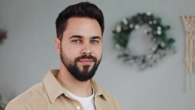 Portrait young handsome bearded man in casual clothes turning head smiling look at camera feel happy on christmas background at home. New year winter holidays. Celebrating Eve. Merry Christmas.
