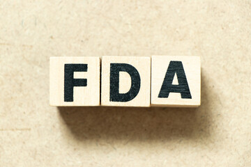 Alphabet letter block in word FDA (abbreviation of food and drug administration) on wood background