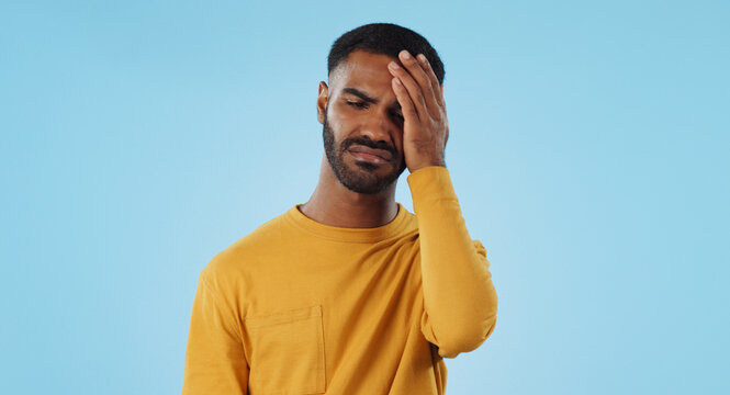 Stress, fail and man in studio with facepalm emoji for stupid mistake or regret on blue background. Anxiety, oops and male model with disaster, crisis or fake news shame, frustrated and unhappy