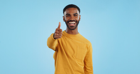 Face, smile and man with thumbs up in studio for support, motivation or vote on blue background. Happy, portrait and excited male model with hand emoji for winning, thank you or success gesture