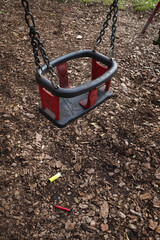 Two brightly coloured electronic cigarette vapes left underneath a child's swing in a play park