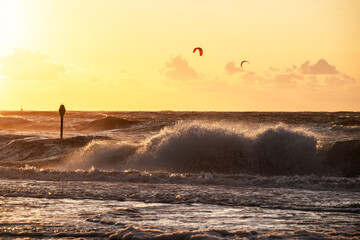 During the sunset at the ocean kitesurfer having fun with stormy weather