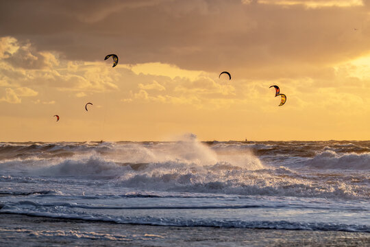 During the sunset at the ocean kitesurfer having fun with stormy weather
