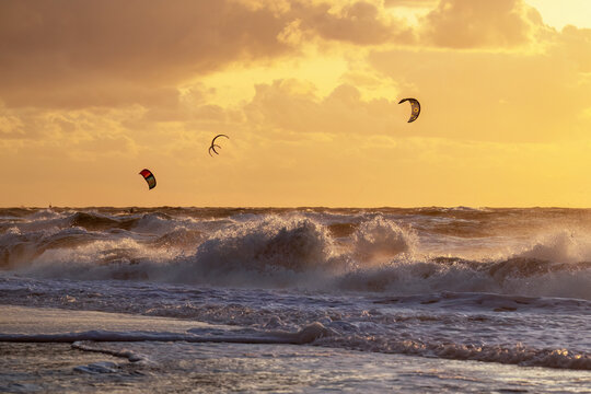 During the sunset at the ocean kitesurfer having fun with stormy weather