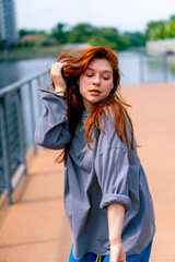 Obraz premium young red-haired street hip-hop dancer in sportswear dances impromptu dance us bridge attract the attention of passers-by hobbies active lifestyle