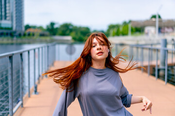 young red-haired street hip-hop dancer in sportswear dances impromptu dance us bridge attract the...