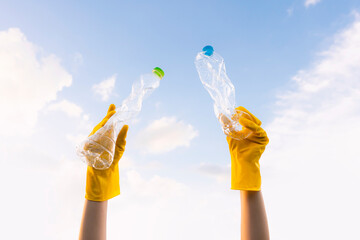 A volunteer cleaning up litter in natural or urban environments picking and lift trashed plastic bottles into the sky. On World Environment Day