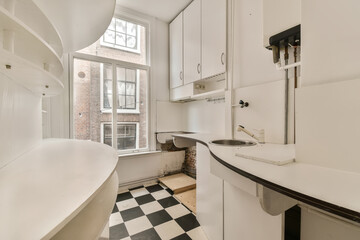 an empty kitchen with black and white checkered tiles on the floor, in front of a large window that looks out onto the