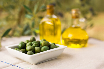 Still life of olives and oil on a table against a background of olive trees