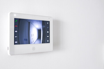 A white video intercom screen on a white apartment wall