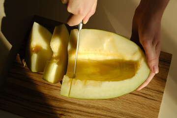 Close-up of female hands cutting a melon into slices