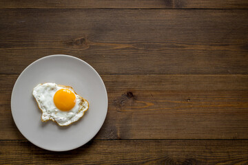 Fast breakfast with one fried egg on plate, top view