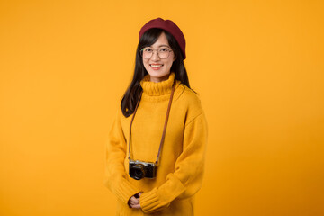 A young Asian woman, creatively capturing memories in her yellow sweater and red beret against a vibrant yellow background.