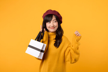 Surprised young Asian woman in her 30s, holding a shopping paper bag, with elegance in a yellow sweater and red beret against a yellow background.