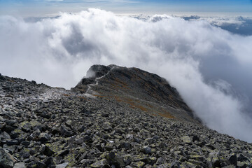 Sea of clouds, above the clouds. Hiking trail to Krywan including highlighted road by light. High Tatras (Tatry) in Slovakia. Foggy environment. A metaphor of a conquered peak. Free space to use. 