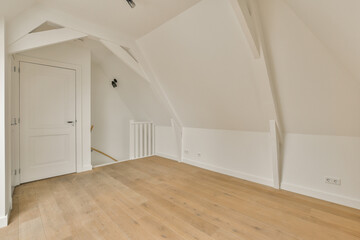an empty room with white walls and wood flooring on the right side, there is a door in the center of the room