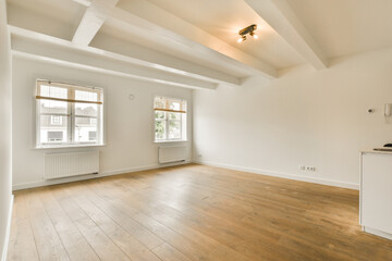 an empty living room with wood flooring and white walls, including two large windows in the room is...