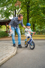 Young father teaches child daughter to ride public bike on one of traffic playground in Prague, Czech republic, Europe