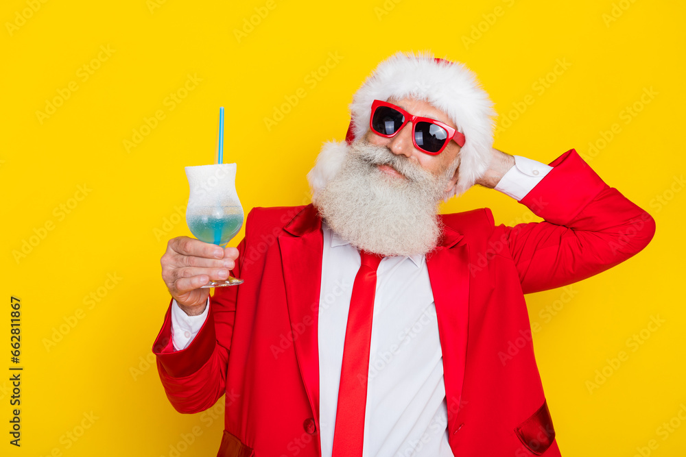 Sticker Photo of peaceful grandfather hand behind head hold drink glass x-mas eve isolated on yellow color background