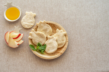 Pomegranate shaped mini pita bread, fresh honey, sliced apples for Jewish holiday Rosh Hashanah on cotton fabric background.
