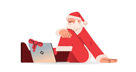 santa claus in red costume sitting on floor and using laptop happy new year merry christmas holidays celebration concept