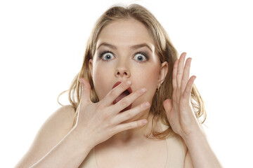 Portrait of young beautiful shocked blonde woman with no makeup on white background