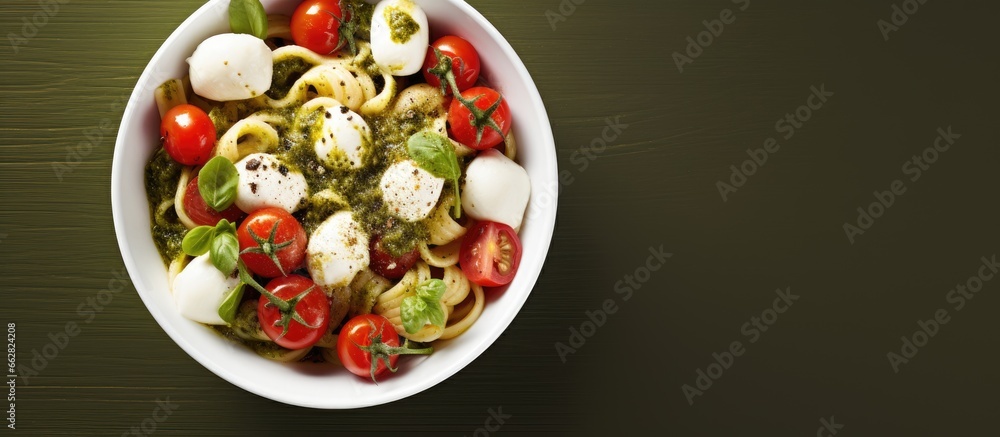 Sticker bowl with pesto pasta cherry tomatoes mozzarella and basil with copyspace for text