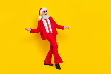 Fototapeta na wymiar Full length photo of funky positive man pensioner dressed red suit santa hat having fun empty space isolated yellow color background