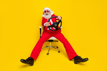 Photo of positive cheerful man pensioner dressed red suit santa hat driving riding vehicle isolated...