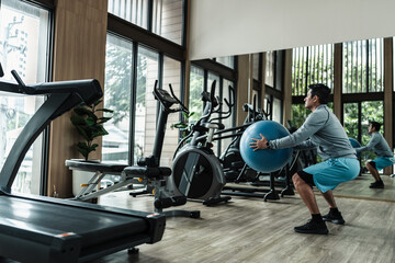 Fototapeta premium A man use pilates ball to squat. Fitness, gym, workout and lifestyle concept.